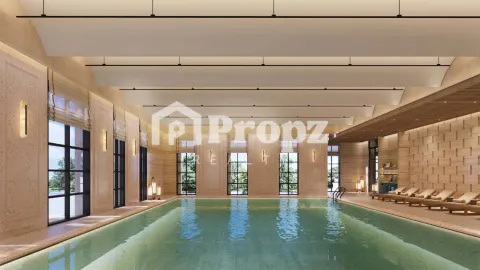 Indoor swimming pool with high ceilings, large windows, and lounge chairs at Lodha Beaumont Estate