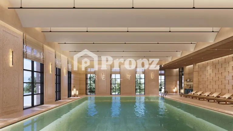 Indoor swimming pool with high ceilings, large windows, and lounge chairs at Lodha Beaumont Estate